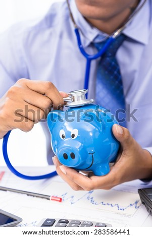 Businessman use stethoscope with piggy bank for financial health check concept