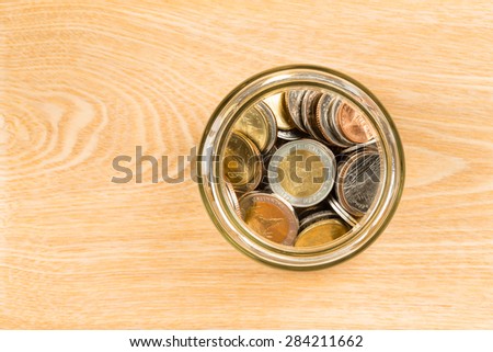 Coin jar on wooden desk top view