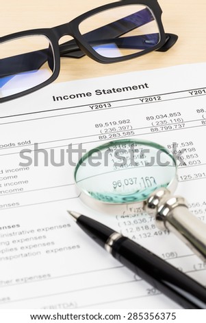 Income statement financial report with pen, magnifier, and glasses