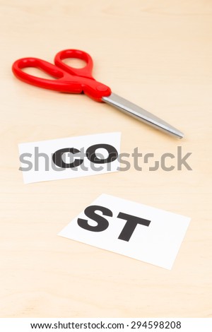 Cost in paper cut by scissor on wooden desk concept cost cut
