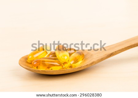 Fish oil capsule food supplement in wooden spoon