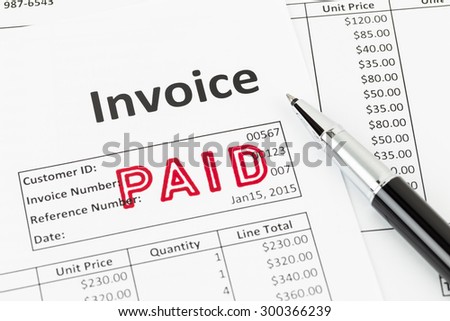 Invoice and pen with paid stamp; invoice is mock-up