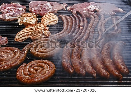 Sausages and pork fried meat, placed on the grill.