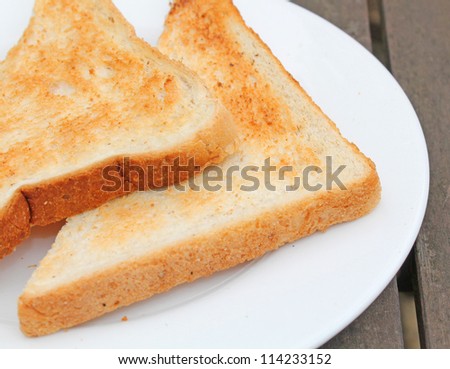 Two pieces of beautiful toast on a white plate on a wooden table