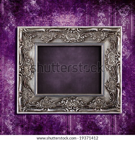 Intricate old frame hanging on grungy violet vintage wallpaper