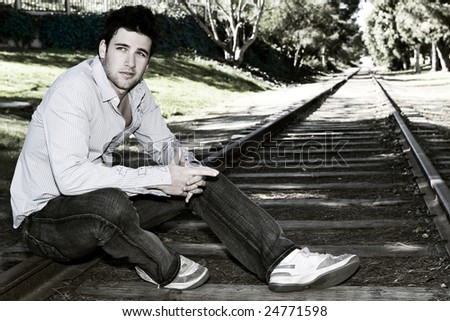 Cross processed man sitting on tracks