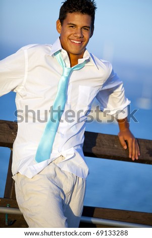 Young man on a pier in a tie at sunset