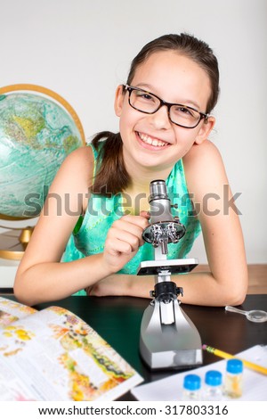 Little girl looking through microscope studying