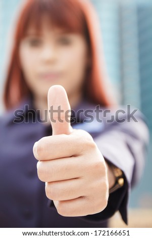 portrait of the smiling asian business woman that shows the thumbs up at modern building