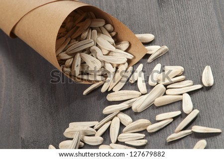 White sunflower seeds in a paper bag on a wooden table