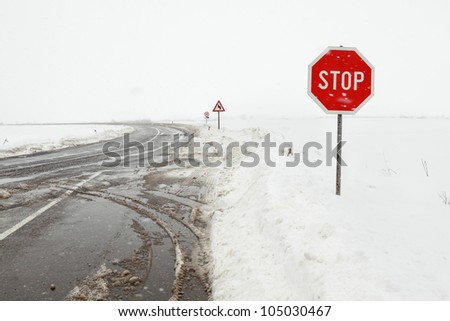 Crossroad in a stormy winter day with stop sign