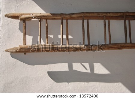 Old ladder on white wall with shadow