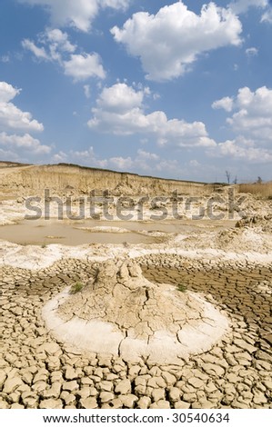 Landscape with cracked dry land and blue sky and white clouds