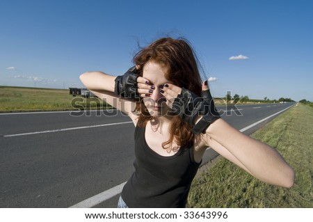 Young teenage girl with hands over eyes side a road