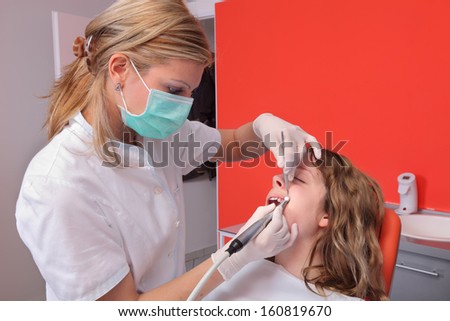 Female dentist doctor cleaning and polishing  young patient tooth