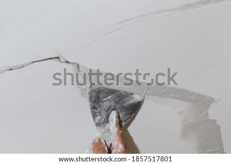 Worker fixing cracks on ceiling, spreading plaster using trowel Photo stock © 