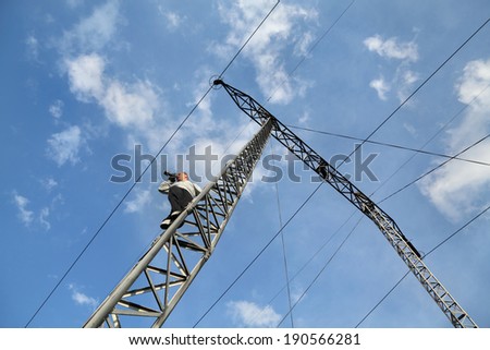 Middle age photographer taking picture  from high voltage electrical pylon, unusual angle