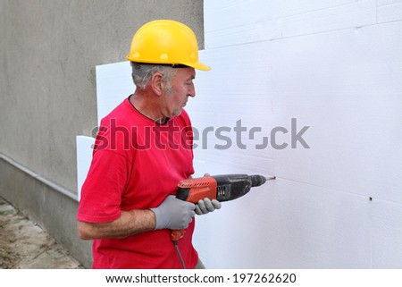 Worker drilling styrofoam sheet insulation on the wall