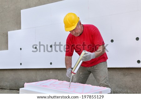 Worker applying polyurethane expanding foam glue with gun applicator