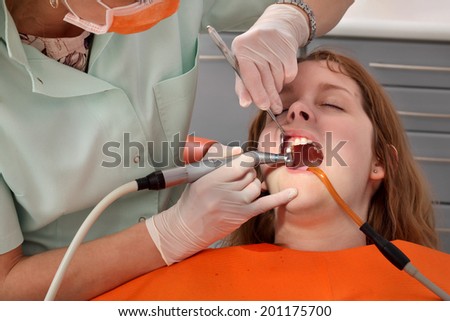 Female dentist doctor cleaning and polishing  young patient tooth