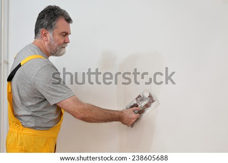 Worker spreading  plaster to wall with trowel, repairing works