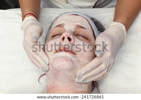 Skin treatment, beautician applying cream to face of young female, real people