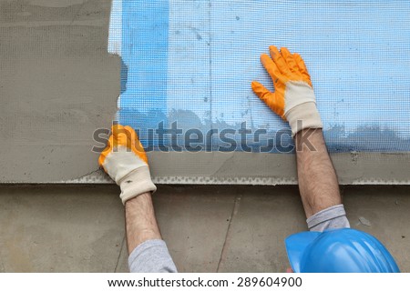 Worker placing mesh over styrofoam insulation and mortar
