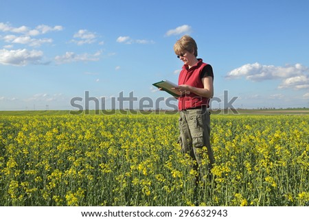 Female agricultural expert or farmer inspecting quality of oil rape