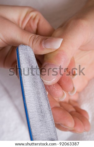 Manicurist filing client\'s nails