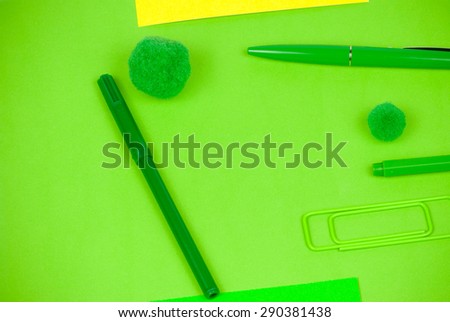 Arrangement of playful vivid office items as green paperclip, writing tools and yellow card, soft fuzzy fluffy balls, symbolizing playful concept on everyday desk work activities excluding computers