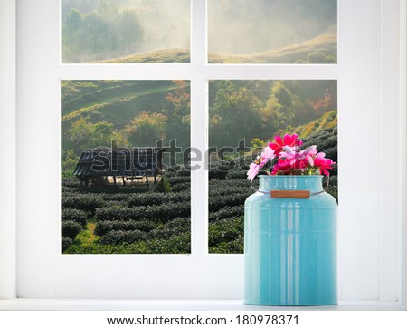 Bouquet of artificial flowers in a window to look through the window at the tea field. relaxation concept