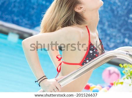 Young sexy girl in beautiful bikini going out of pool