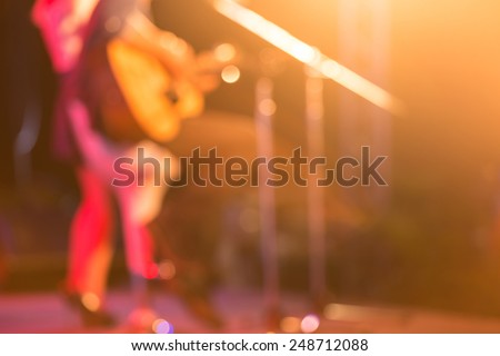 blurred woman guitar player on concert stage
