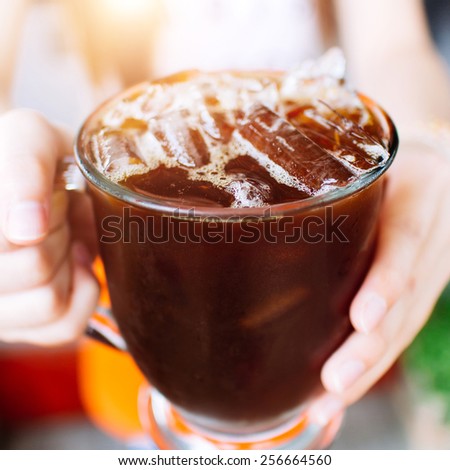 glass of cold coffee and asian women hand
