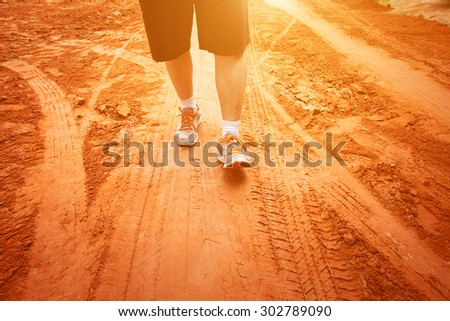 legs of sport man walking on the mud path
