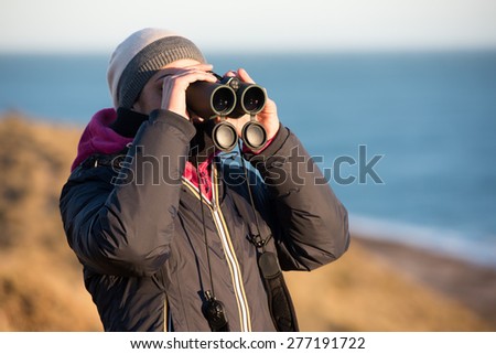 girl looking sea from cliffs with binoculars