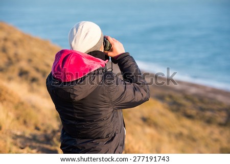 girl looking sea from cliffs with binoculars