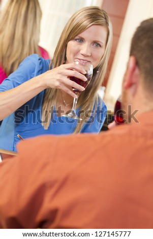 A happy woman having a glass of wine at a restaurant.