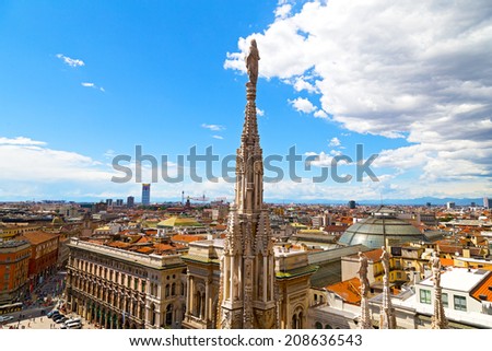 A statue of the Dome of Milan cathedral with the city view in summer. Aerial view of Milan downtown from height of dome steeple.