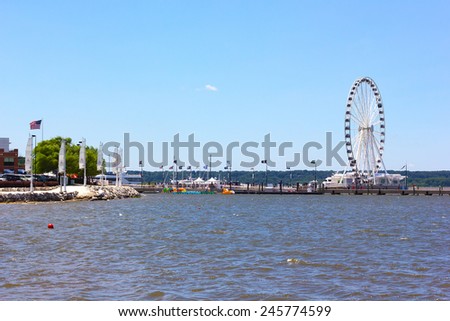NATIONAL HARBOR, USA - JULY 4, 2014: Harbor pier with Ferris and the waterfront development on July 4, 2014 in National Harbor, USA. The town located along the Potomac River in Prince George\'s County.