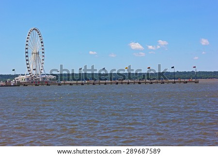 Ferris of National Harbor and a long pier in Maryland, USA. National Harbor waterfront with pier on a bright sunny day.