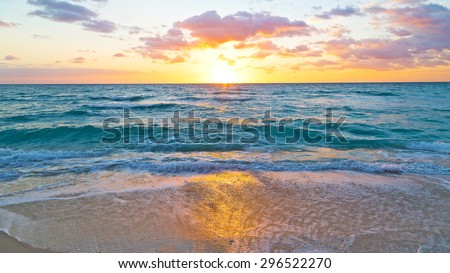 Sunrise reflection on the beach sand. Golden sunrise at ocean beach.