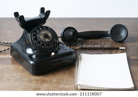 Old phone with writing pad for Copy Space and pencil on a desk.