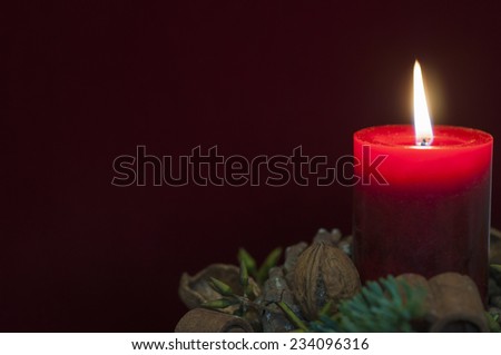 Background Christmas decoration, red candle with candlelight in front of red velvet and copy space.