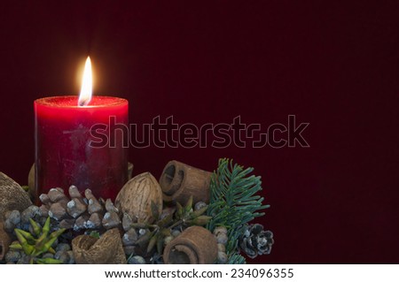 Background Christmas decoration, red candle with candlelight in front of red velvet and copy space.