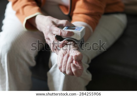 Old woman reading her blood pressure meter from the arm.