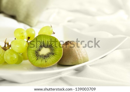 Healthy dessert served directly to bed - green fruits on white background. Good diet.