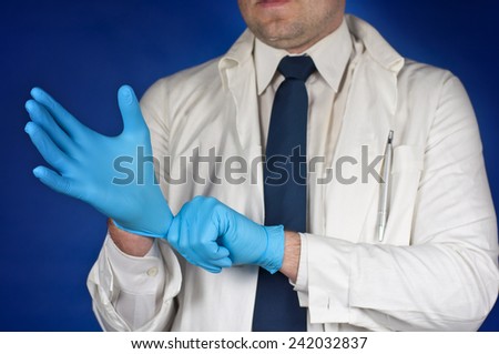Medicine doctor putting on protective gloves before examination isolated on blue background
