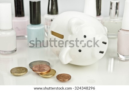 Broken on cosmetics - piggy bank with dropping euro coins and nail polish in the background
