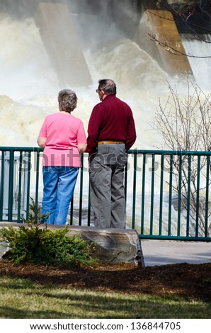 BRACEBRIDGE ONTARIO - APRIL 28, 2013: Elderly couple watching the Muskoka River Hydro Falls during the worst flood in hundred years below the Hydro station on April 28, 2013 in Bracebridge, Ontario.